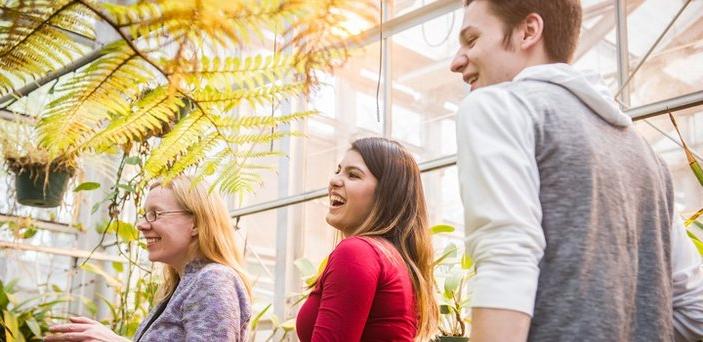Professor and students in greenhouse surrounded by plants